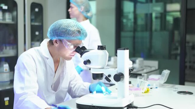 Scientists examine samples with microscope in laboratory on a weekday