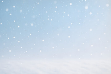 Snowflakes gently falling over a pale blue sky and white snow-covered ground, creating a peaceful winter backdrop..