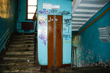dilapidated stairwell and elevator entrance in an old residential building. Neglected building entrance with poor maintenance. Urban decay, social studies projects, crime drama backdrops. © Kate