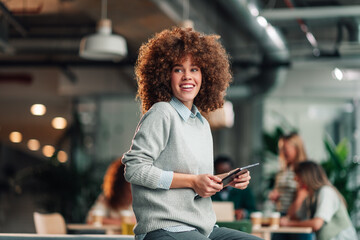 Young businesswoman smiling holding tablet in office