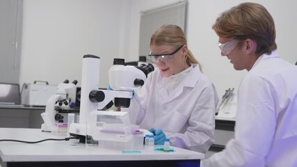 Students work on experiments using a microscope in a laboratory setting - Powered by Adobe