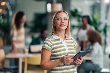 Confident businesswoman wearing glasses holding digital tablet