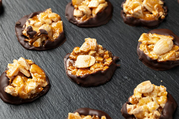 Chocolate Florentines cookies with almonds on a stone board.