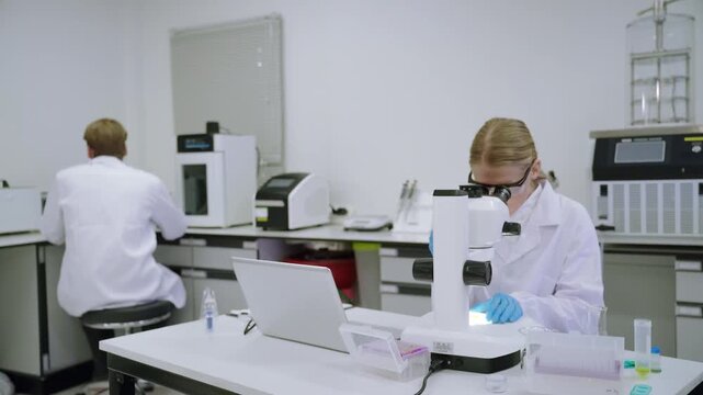 Research in a laboratory with scientists using a microscope and other equipment