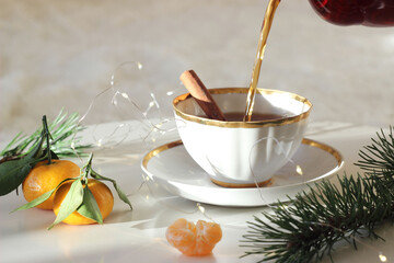 Black tea is poured into a cup. New Year's decor