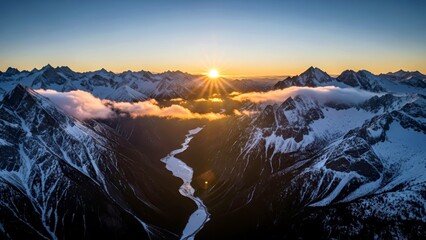 Sunrise over snow-covered mountains with river valley below  