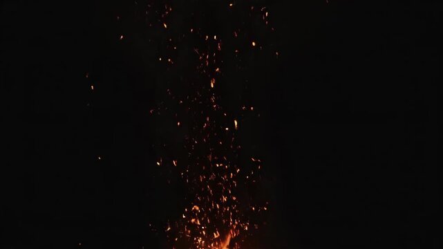Fire sparks and embers explode and float in slow motion. A dynamic burst of flames on a black background for compositing