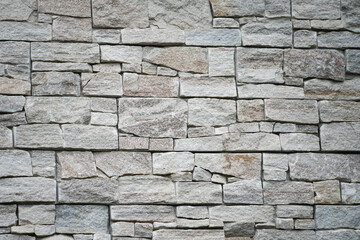 Natural granite stone wall with rougly surface, alignment in horizontal layer. Building exterior bacground or texture.