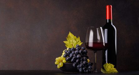 Obraz premium Red wine bottle with a glass and basket of fresh grapes