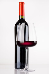Obraz premium Red wine bottle and glass on white background
