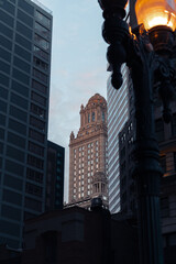 Historic tower framed by modern skyscrapers at sunrise in downtown Chicago. Modern architecture.