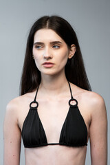 Young female fashion model in clean studio environment showing digitals and modelbook snaps for agency profile portfolio in bikini, frontal and profile angles	
