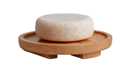 Solid shampoo bar with textured surface resting on a wooden soap dish on white background for eco friendly bathroom routine