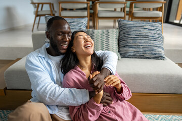 Happy and diverse couple sharing a joyful moment at home, embracing and smiling together