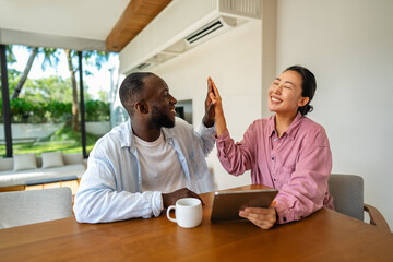 Overjoyed multiethnic couple using laptop, shopping online with sales, playing game together