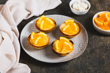 Tartlets baked with cottage cheese and orange on a plate on the table
