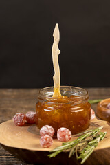 orange jam made from oranges and fresh citrus fruits, orange jam with dried kumquat fruits in sweet sugar syrup, sweet jam for making desserts in a round glass jar on a wooden table