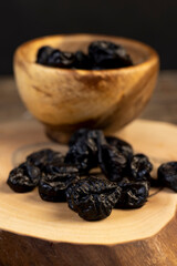 black soft dehydrated fruits of plums, prunes scattered on the kitchen table, black sweet seedless prunes scattered on the table