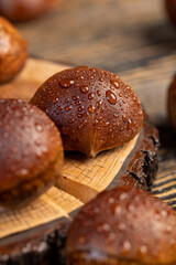 a hard edible chestnut fruit in a brown shell covered with water droplets on a wooden table, a group of wet chestnut fruits with a brown hard shell
