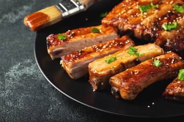 Hot grilled spare ribs from a summer BBQ served on a plate with sauce. Top view. Copy space