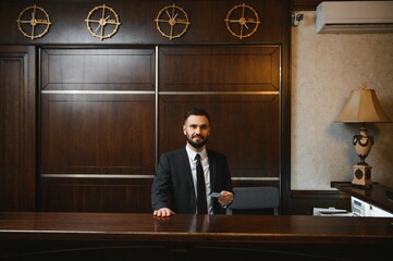 Male hotel receptionist holding key card at desk