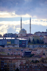 Breathtaking view of a majestic mosque in Istanbul, framed by two tall minarets, overlooking the vast, densely populated urban area under a powerful, textured cloudscape. Ideal for Turkish travel.