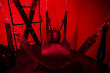 Sex swing in red light. BDSM equipment.