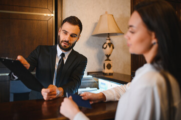 Hotel receptionist assisting female guest checking in
