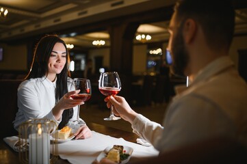 Young couple celebrating romance, toasting red wine during dinner