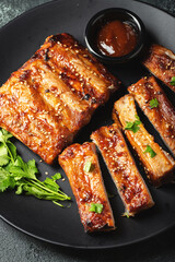 Hot grilled spare ribs from a summer BBQ served on a plate with sauce. Top view. Copy space