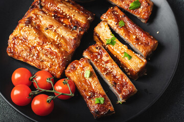 Hot grilled spare ribs from a summer BBQ served on a plate with sauce. Top view. Copy space