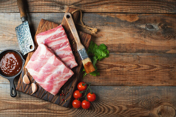 Raw pork ribs with spices, salt and rosemary on dark wooden background