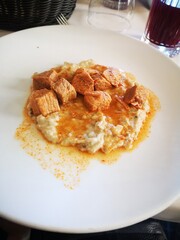 Savory dish featuring tender meat chunks served on creamy grain base, garnished with spices, showcasing culinary artistry and vibrant presentation