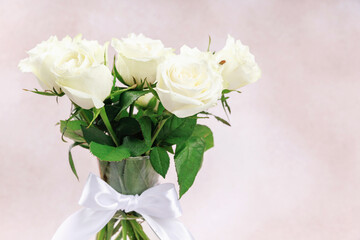 White rose bouquet in glass vase on pastel background with empty space for text