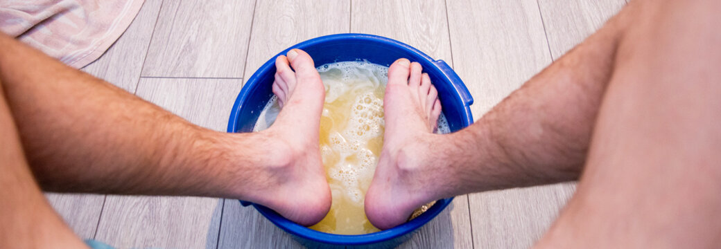 A man soaks his feet in water with mustard plasters during a cold to prevent complications and speed up recovery.