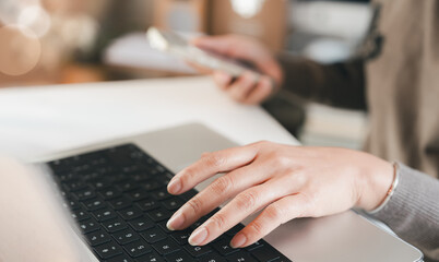 Closeup business woman hands typing on laptop keyboard while holding smartphone, surfing internet, teleworking, searching information, global network, and email marketing communication.