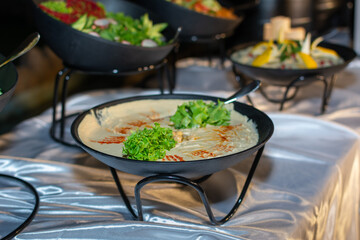 Creamy Arabic hummus dip garnished with fresh greens at a catered event.