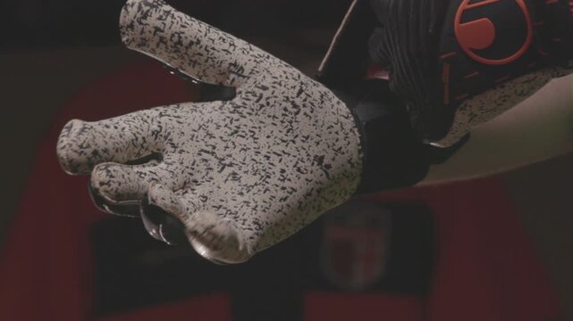 Close-up of an African American football player pulling up orange socks over his knees. The athlete is getting dressed and preparing for a soccer match in the locker room.


