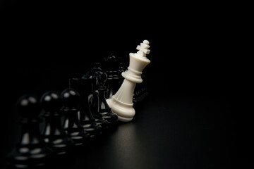 White chess king standing alone against opposing black pieces representing resistance, disruption, minority challenge, and strategic defiance in competitive or business environments.