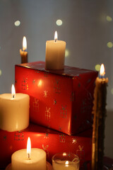 cozy festive scene with glowing candles casting warm light on red gift boxes adorned with silver patterns, evoking a tranquil holiday atmosphere against a soft bokeh background, timeless, fire