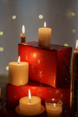 cozy holiday scene with burning white candles on red gift-wrapped boxes featuring sparkling designs, creating a warm and festive ambiance against a soft bokeh background, relaxation, settings, dim