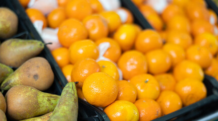 Ripe, freshly picked tangerines in a box at a farmer market. Abundant supermarket window with citrus fruits close up