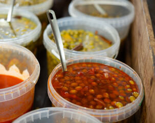 Marinated olives in plastic containers on a shelf in a supermarket