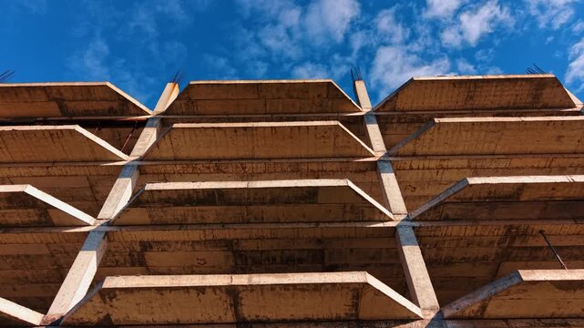 Multi-storied building floors from low angle perspective. Blue sky with light clouds at backdrop.
