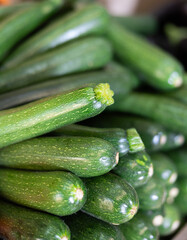 Pyramid of zucchini is laid out on shop window. Various varieties of green marrow squash are presented in greengrocers shop. .