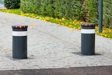 Retractable bollards providing security and traffic control on a paved sidewalk in an urban green space area