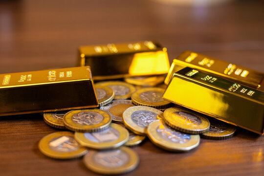  Image displays Ghanaian 1 and 2 Cedi coins arranged among polished gold bars. These bimetallic coins feature the Scale of Justice and the Jubilee House , set against the reflective gold bullion.