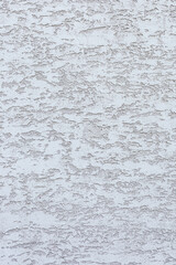 A textured white wall with subtle patterns and variations in tone. The surface appears rough and uneven, creating an interesting visual effect.