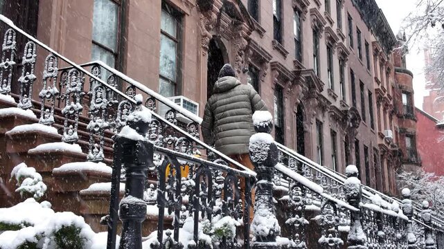 another tighter shot of man shoveling snow on stoop in front of Brooklyn brownstones