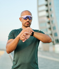Portrait opf a young man prepering to exercise and run and looking at watch in sportwear posing for a portrait outdoors